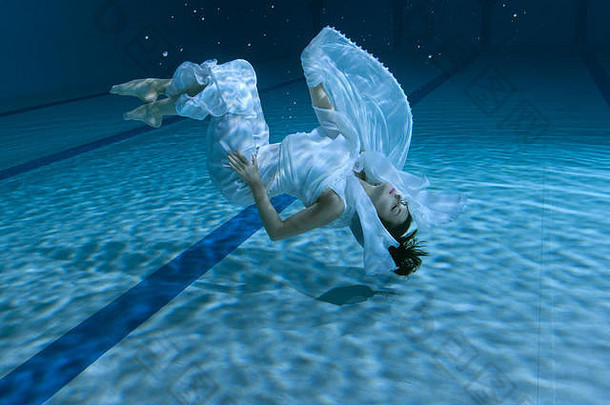 女人在水下表演，她在游泳池的底部。