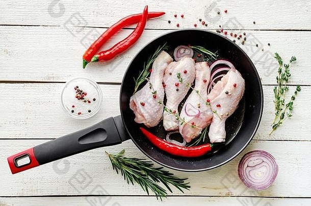 在煎锅中加入香料和香草的生腌制鸡腿或鸡腿，准备烹饪。地中海食品概念。俯视图