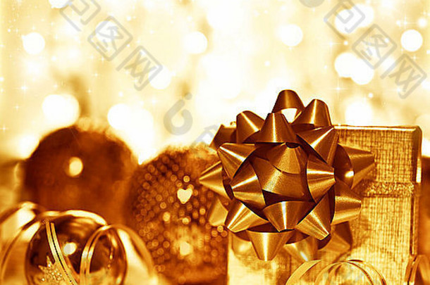 圣诞金色礼物装饰，圣诞树球饰品，在模糊发光的波基灯背景上有礼品盒