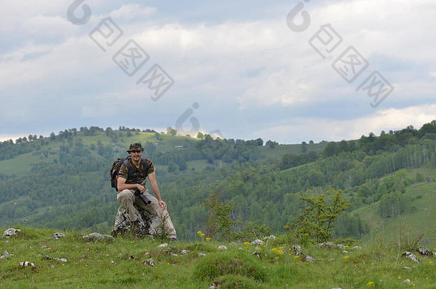 快乐的旅行摄影师在一座以绿色景观为背景的山丘上