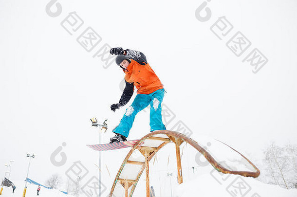 年轻运动型男子用跳板在滑雪板上滑雪的照片