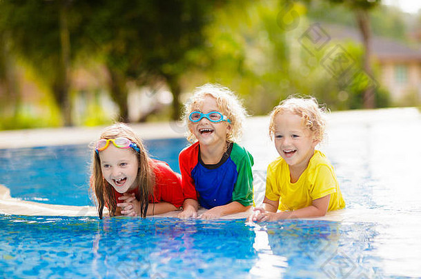孩子们在游泳池里玩。家庭暑假期间，孩子们在热带度假胜地的室外游泳池里学习游泳。水和飞溅的乐趣，为年轻的基
