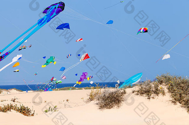 夏天，五颜六色、形状各异、大小各异的风筝在沙滩上飞翔。