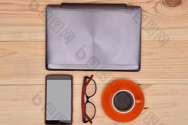 把笔记本电脑、手机、眼镜和咖啡放在木桌上