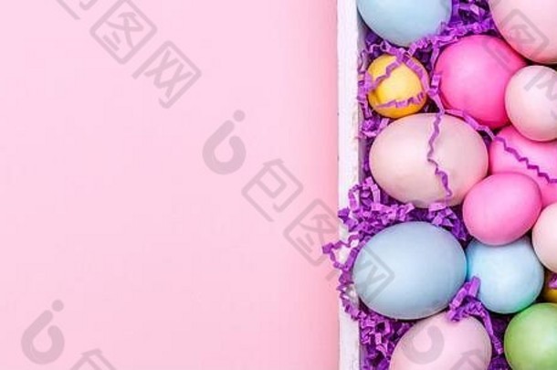 白色托盘中的彩色鸡蛋。创意复活节概念。现代纯色粉红色背景。横幅格式
