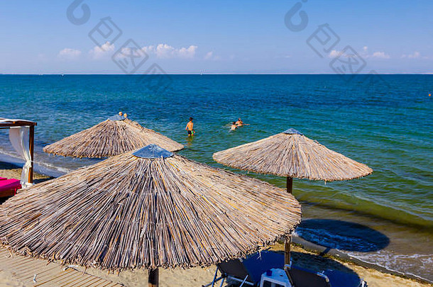 上图：遮阳棚、雨伞和塑料躺椅放置在公共海滩上，是一个完美的假日。