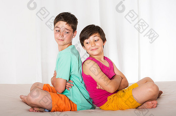 两个小男孩坐在床上互相靠着