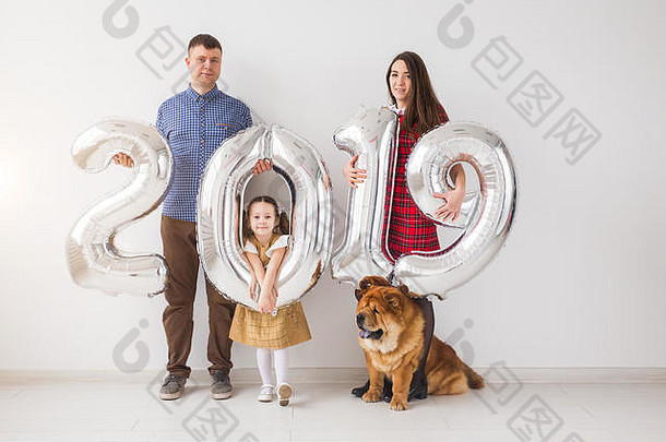2019年的新概念即将到来——欢快的母亲、父亲、女儿和狗在室内手持银色数字。