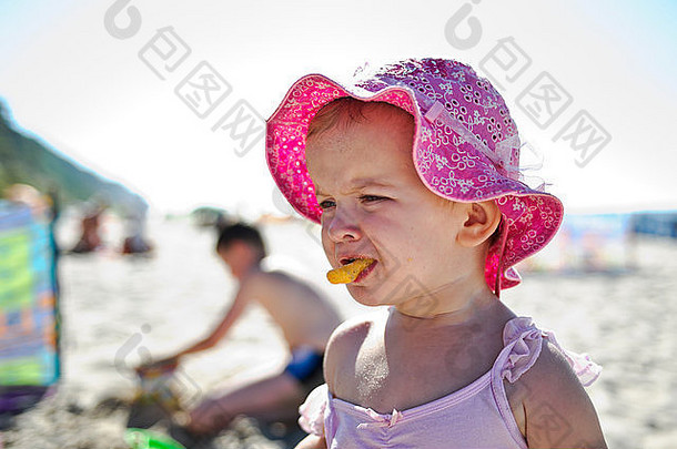 海滩上吃薯片的小女孩
