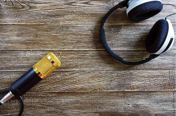 电容式金话筒和耳机放在一张有复印空间的木桌上。音乐主题。平铺。顶视图。