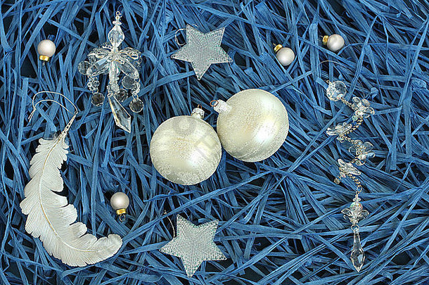 圣诞装饰-蓝纸拉菲背景上的银色和玻璃质玩具