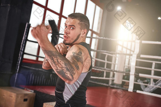 穿着运动服的年轻肌肉男运动员的特写镜头在黑拳馆投掷上勾拳和打太极拳