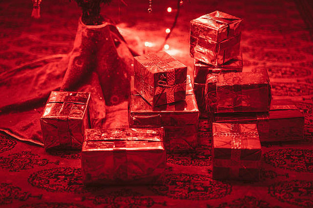 圣诞树下的手工圣诞礼物。红色圣诞灯照亮了礼品盒。