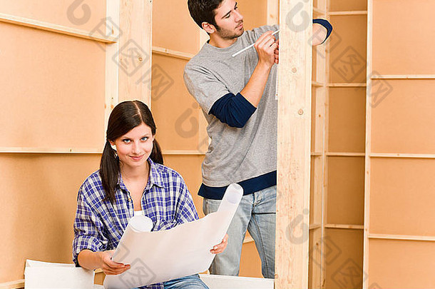 家装幸福年轻夫妇用建筑蓝图修缮房子