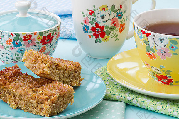 下午茶或高茶蛋糕和一杯茶花陶器。花杯碟中的煎饼和茶作为点心