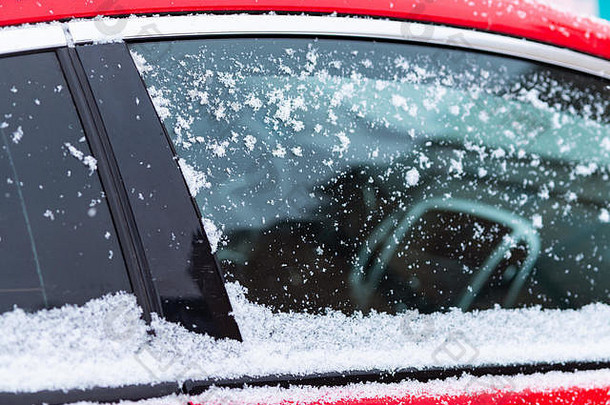 积雪覆盖的车窗，微距，特写。没有使用防冻剂。雪地里的车辆。冬天快到了。恶劣的天气条件