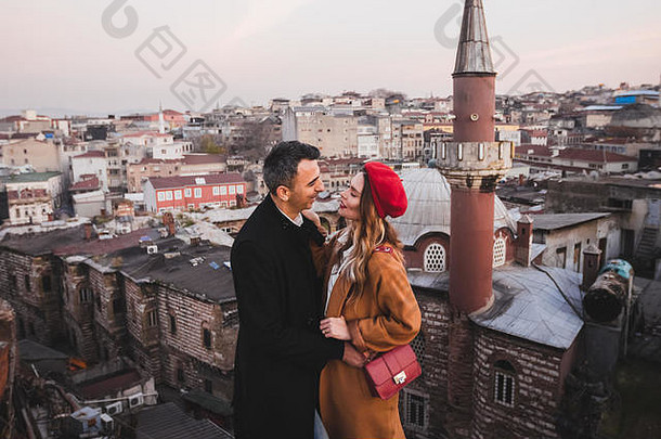 夫妇爱拥抱屋顶视图晚上城市背景休闲风格秋天红色的贝雷帽米色外套