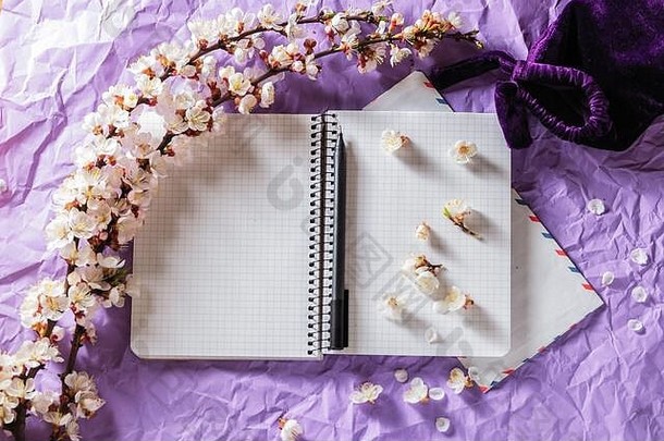 在明亮的背景上打开空白笔记本、钢笔和樱花枝。写信、通信概念