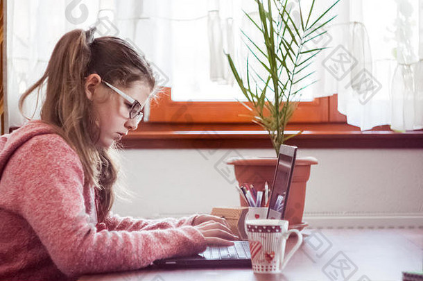 美丽可爱的金发小女孩戴着眼镜，穿着紫色连衣裙，在<strong>笔记</strong>本电脑上工作和玩耍