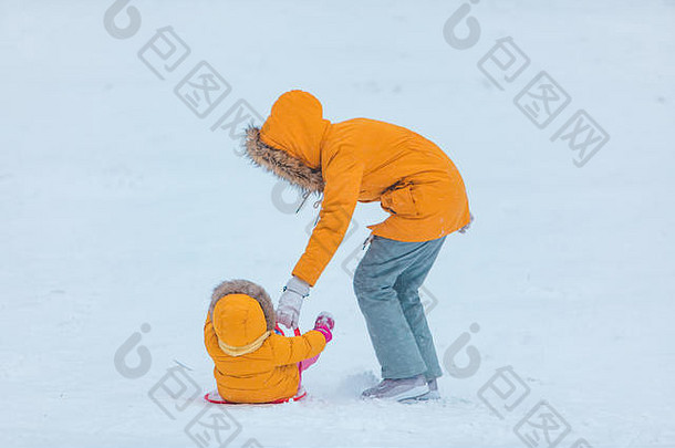 母亲和女儿从冬山上滑下来