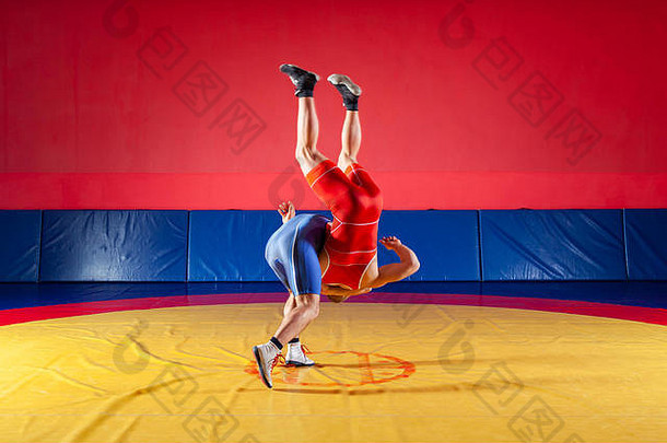 两个穿着蓝色和红色摔跤紧身衣<strong>的</strong>年轻人正在体育馆<strong>的</strong>黄色摔跤地毯上进行摔跤和超级摔跤。公平<strong>的</strong>概念