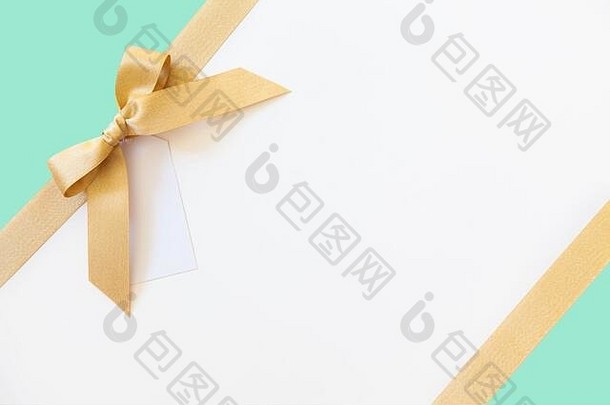 以白色和薄荷色为背景，配以蝴蝶结作为礼物的金丝带