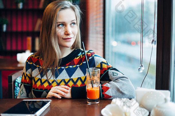 一位妇女透过窗户喝果汁的照片