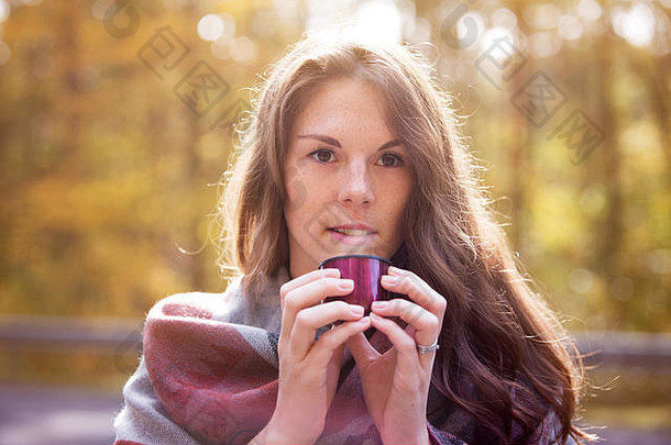 肖像年轻的女人喝杯秋天