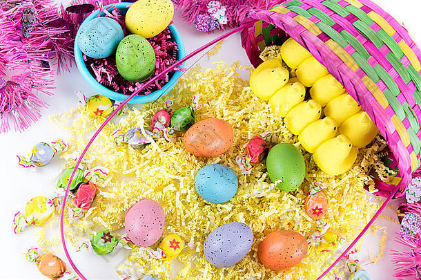 篮子里有彩色复活节彩蛋、黄色小鸡和糖果