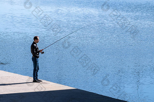 yoshkar-ola大禾俄罗斯城市渔夫钓鱼杆男人。站混凝土海滨清晰的蓝色的河城市