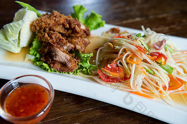 菜泰国炸鸡绿色木瓜沙拉白色板小碗热酱汁黑暗木表格