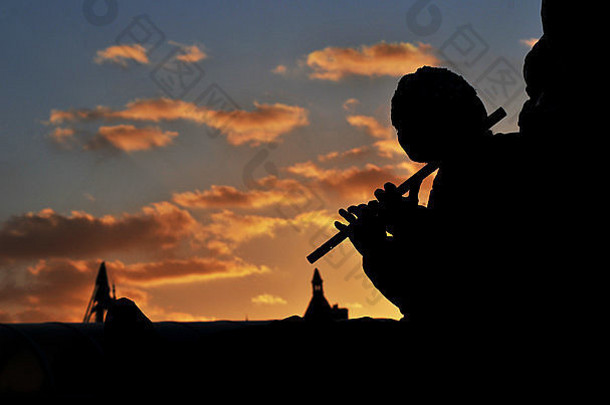 一位长笛手在泰晤士河岸边吹奏长笛