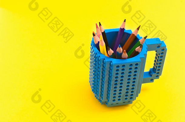 黄色背景上桶里的彩色铅笔。回到史酷尔的概念。