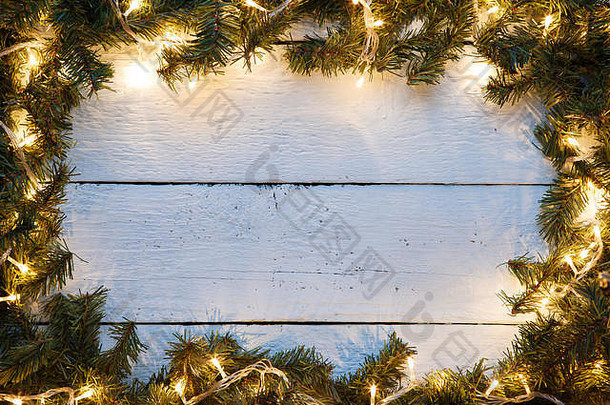 圣诞和新年木质背景装饰着冷杉树枝和发光的花环。带复印空间的假日卡