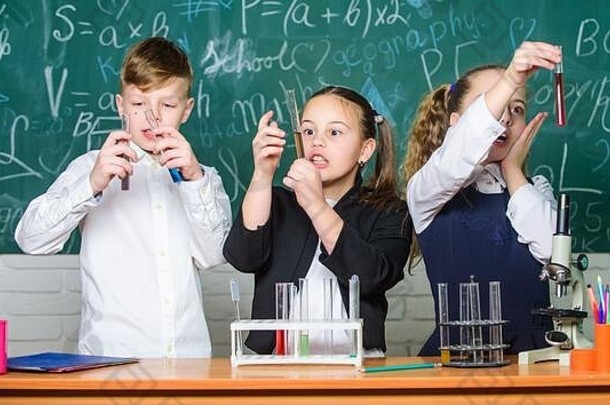 液体状态的研究。小组学校的学生学习化学液体。女生和男生用液体做实验。检查结果。团队合作理念。带有彩色液体物质的试管。