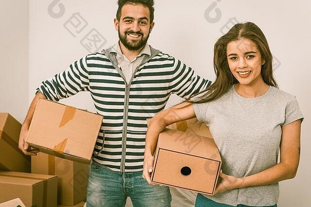 年轻的夫妇微笑持有盒子站打开盒子