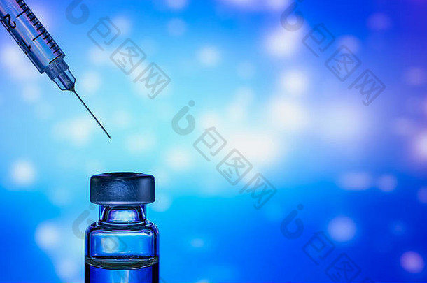 一个针头指向彩色抽象背景上的疫苗瓶的注射器