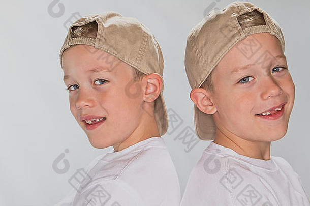 6岁的同卵双胞胎戴着棒球帽微笑着