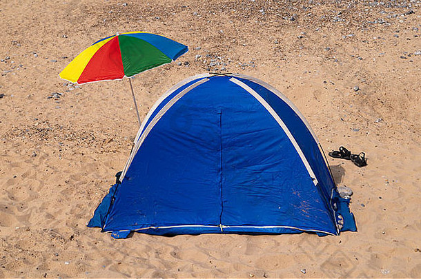 英国东英格兰诺福克海滩上的蓝色帐篷，带彩色雨伞