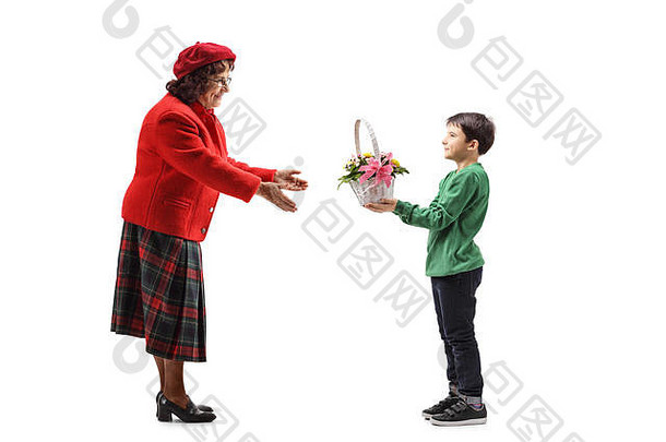 在白色背景上，一个小<strong>男孩</strong>给他的祖母一个装满花的篮子的全长照片