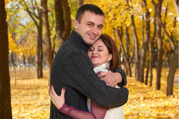 浪漫的人，快乐的成年夫妇在秋天的城市公园拥抱，黄叶的树木，明亮的阳光和幸福的情感，温柔