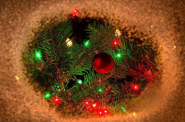 红色的圣诞装饰品和挂在真正的冷杉树枝上的灯，雪边。夜间圣诞季节概念。