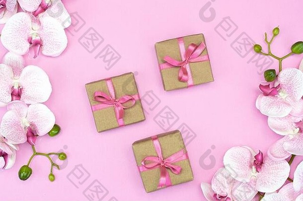 粉色丝带、粉色背景上的兰花礼品盒。春天的概念。拷贝空间