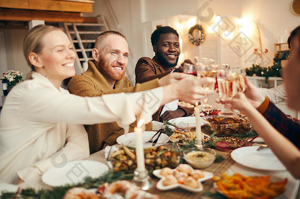 多民族的人们举杯庆祝圣诞节，朋友和家人坐在美丽的餐桌旁