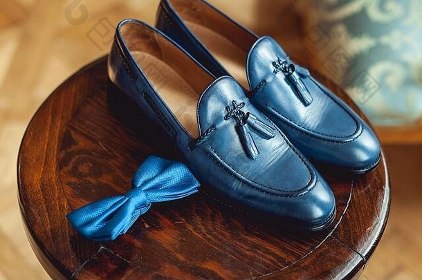 木制圆凳上的蓝色鞋子和蝴蝶结。礼服的配饰。男士优雅时尚的象征。