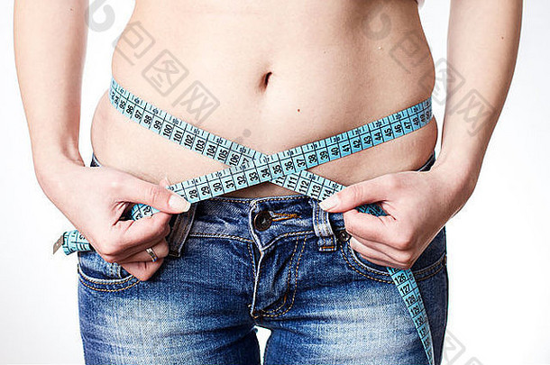 年轻的女人牛仔裤测量腰磁带