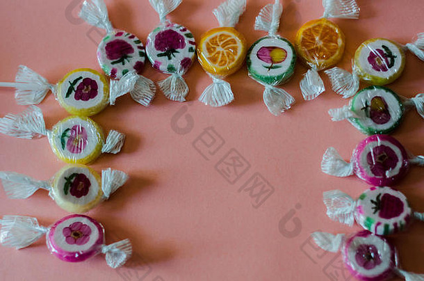 粉红色背景的彩色水果棒棒糖，不健康但美味的儿童零食，糖果