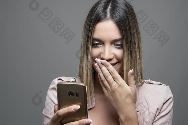 美女在手机上读短信，捂着嘴笑。