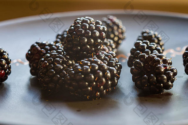 陶瓷盘上的大型多汁新鲜黑莓浆果，特写
