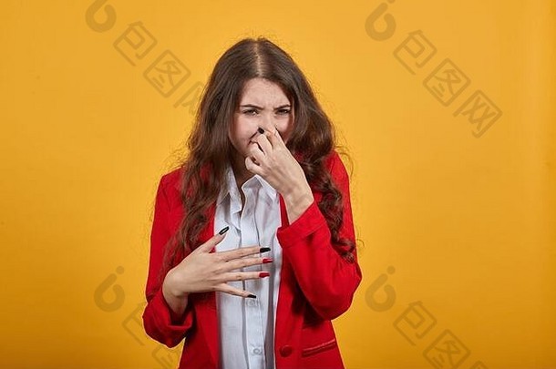 一个穿着白衬衫和红夹克的不开心的女人捂住了鼻子以防臭味